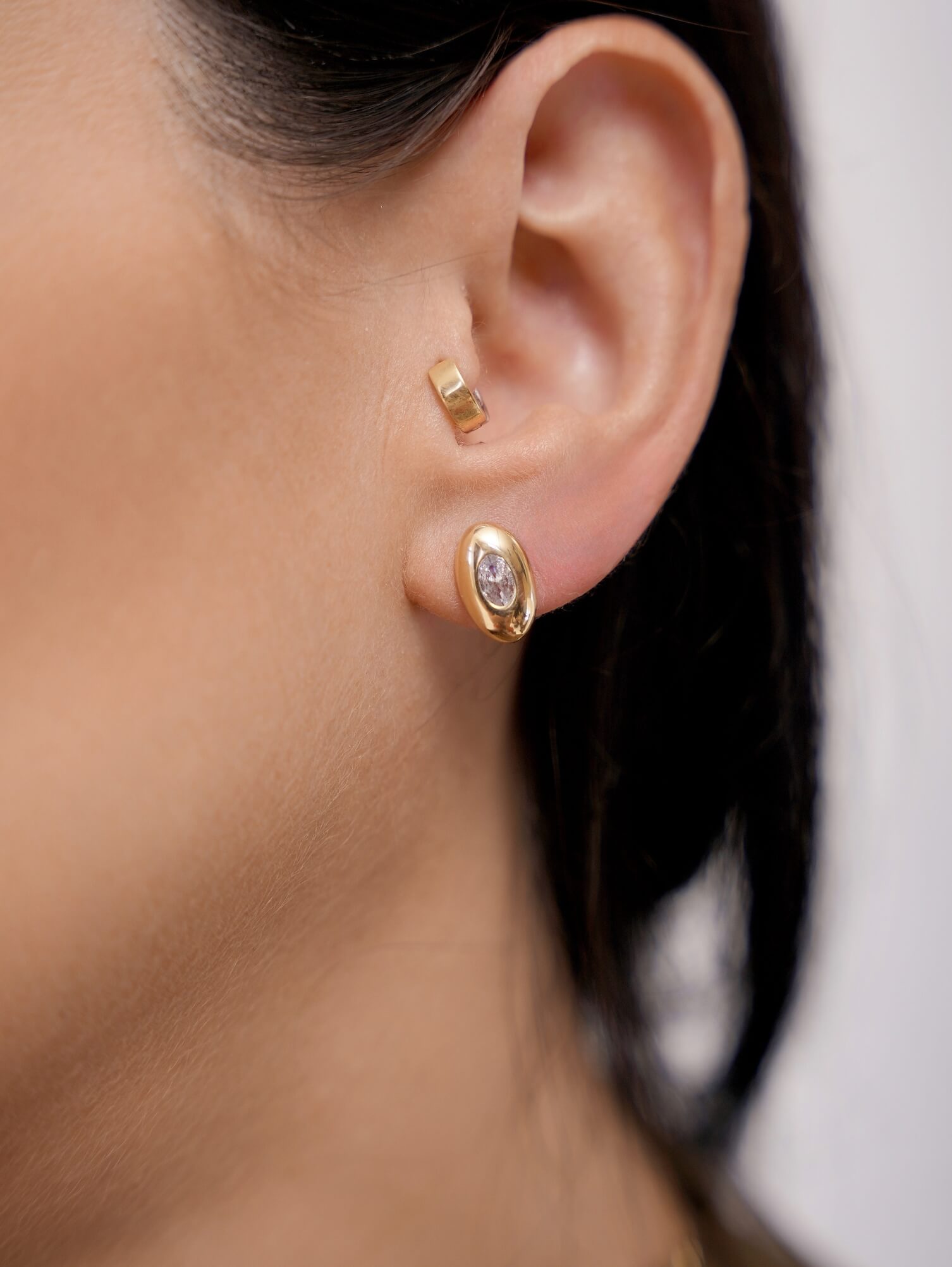 brinco bold oval em ouro 18k com topázio incolor no lóbulo da orelha