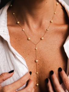 Colar gravatinha com pérolas naturais e ouro 18k no colo feminino