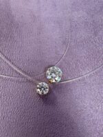 Pingente avulso ponto de luz moissanite em ouro 18k sobre superfície lilás.