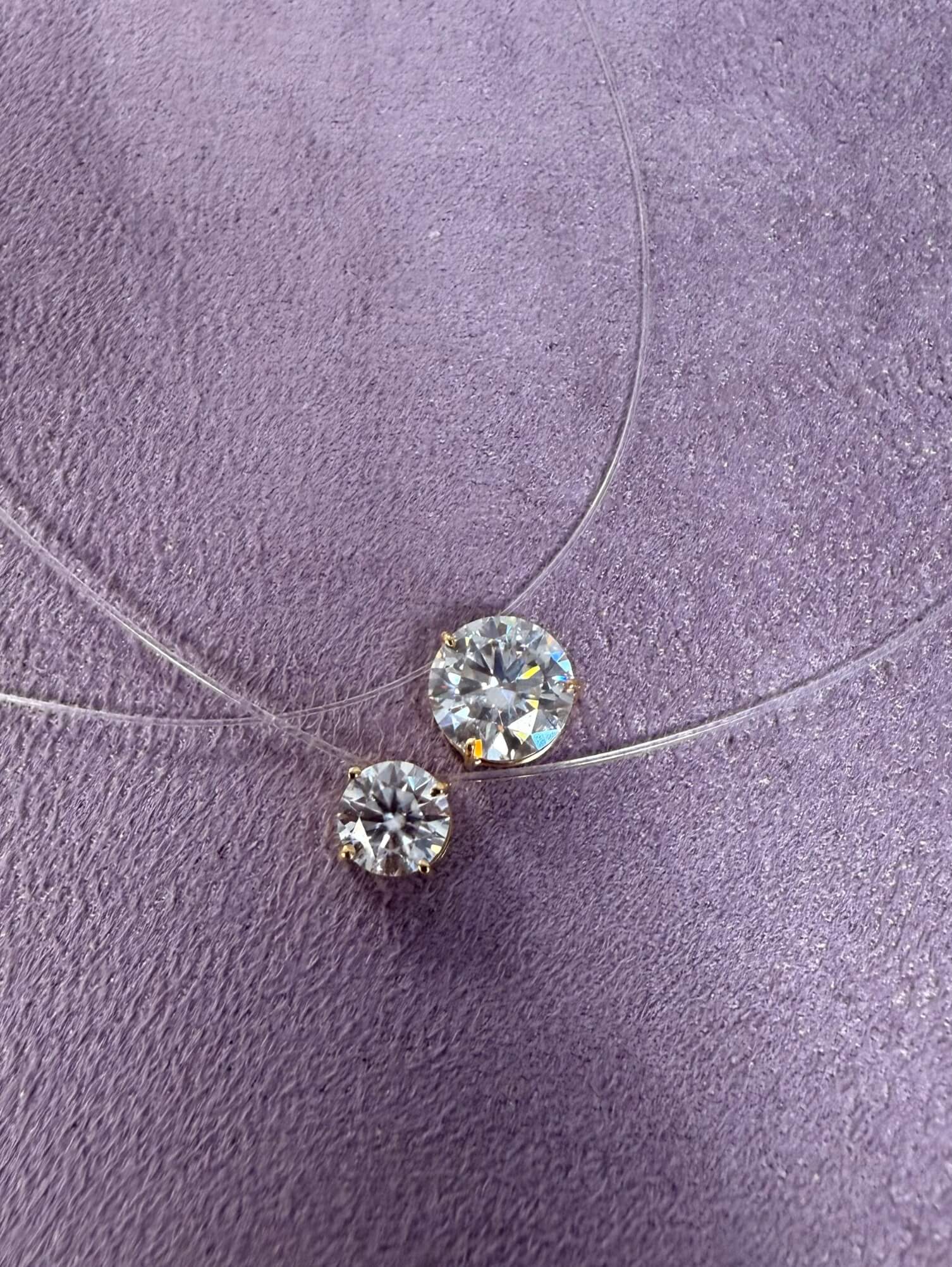 Pingente avulso ponto de luz moissanite em ouro 18k sobre superfície lilás.