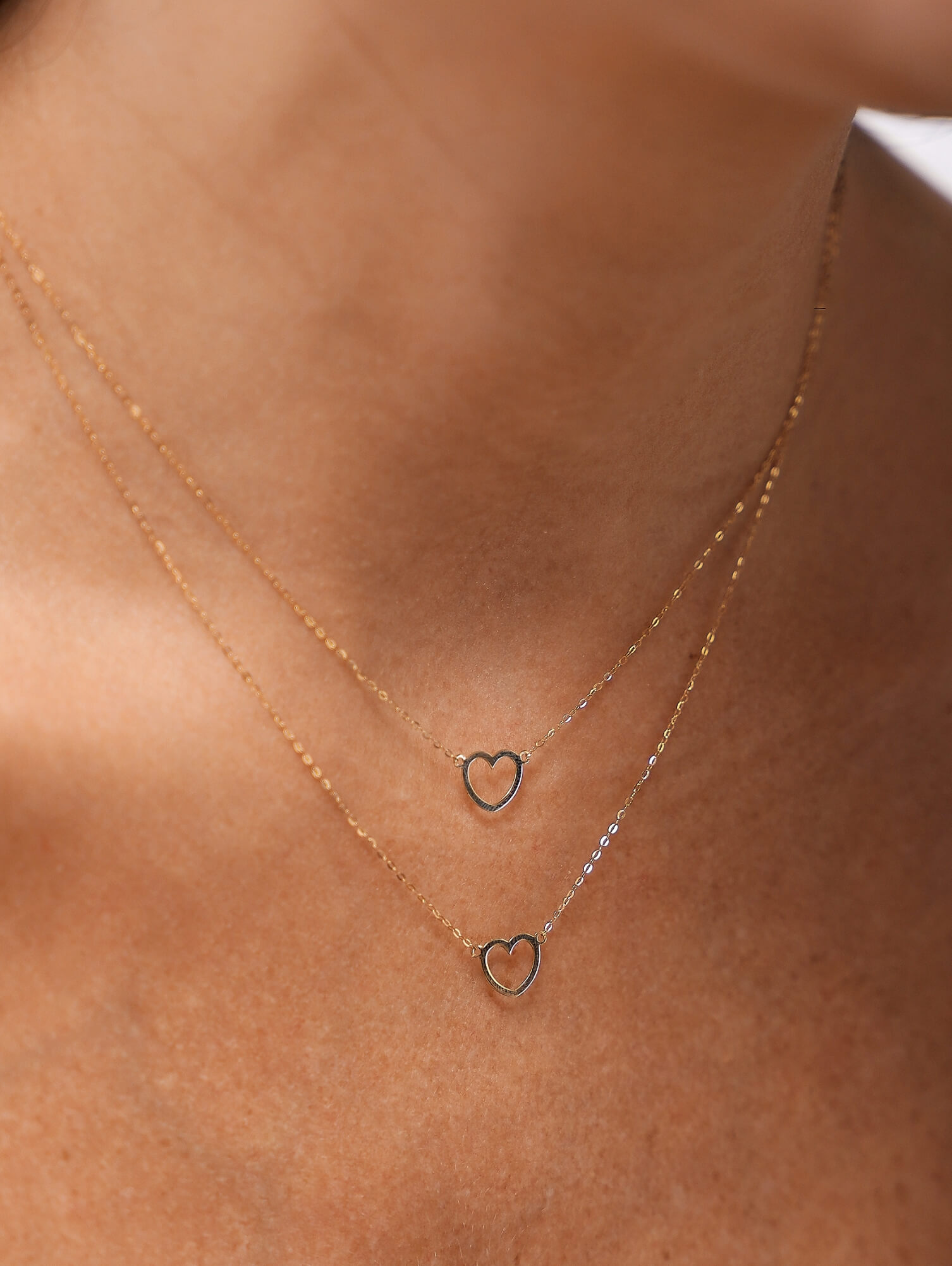 colar coração vazado em ouro 18k com corrente cartier no colo feminino