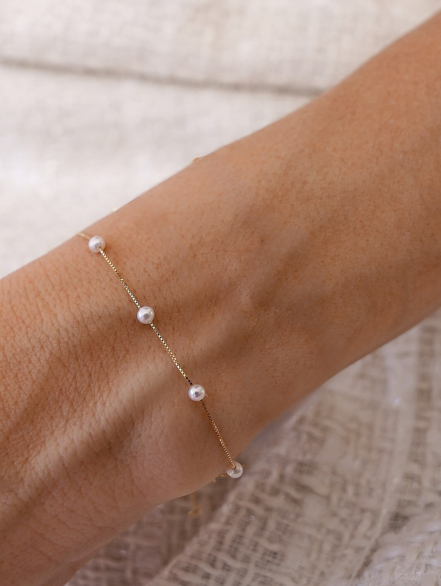 pulseira com pérolas espaçadas em corrente de ouro 18k no pulso feminino